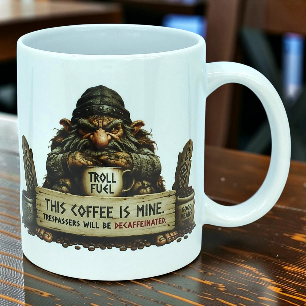 Ceramic coffee mug featuring a Nordic folklore troll holding a cup of coffee, with the text: This coffee is mine. Trespassers will be decaffeinated. Troll fuel.