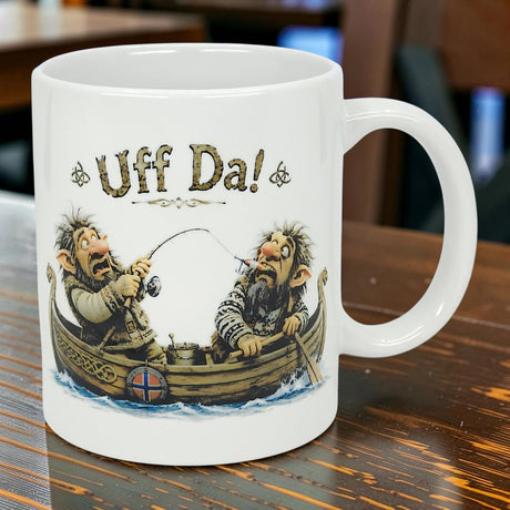The Mug: Uff Da Fishing Trolls Ceramic Mug (11 oz) by Nordic Wholesale features two cartoon trolls fishing in a boat with a Norwegian flag and “Uff Da!” text—an ideal collectible for fans of Scandinavian designs.