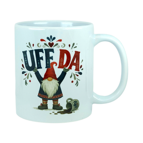 White ceramic mug with the text Uff Da and an illustration of a Scandinavian tomte gnome standing next to a spilled mug.