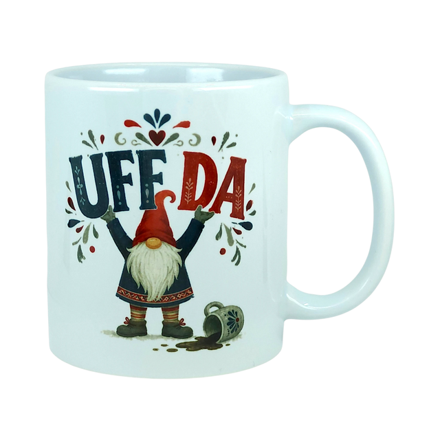 White ceramic mug with the text Uff Da and an illustration of a Scandinavian tomte gnome standing next to a spilled mug.