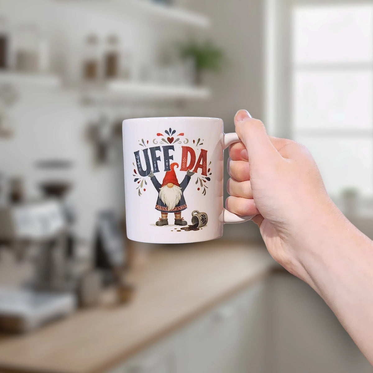 A hand holds a white mug with a tomte gnome illustration, a spilled drink graphic, and the text Uff Da.