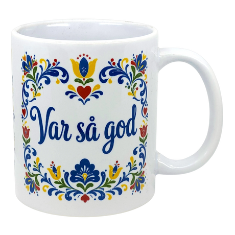 White Scandinavian mug with colorful floral patterns and blue text “Var så god” in the center.