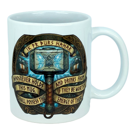 The Mug: Viking Energy of Thor Ceramic Mug (11 oz) by Nordic Wholesale is a white mug showcasing Thor’s hammer with intricate Norse designs and the inscription: “Whosoever holds this mug and drinks from it, if they be worthy, shall possess the energy of Thor.”.