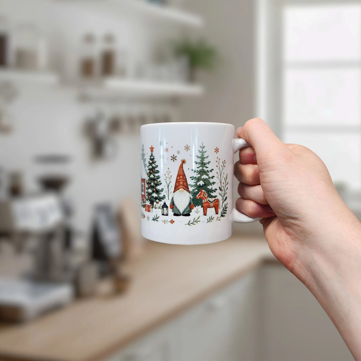 A hand holds the Nordic Wholesale Mug: Winter Tomte and Dala Horse Ceramic Mug (11 oz), featuring festive Scandinavian gnomes, Dala horses, and wintry designs in a bright kitchen background.