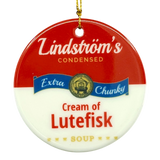 Round ornament styled like a soup can label, text reads Lindströms Condensed Extra Chunky Cream of Lutefisk Soup, gold hanging string attached.