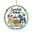Round ceramic ornament featuring Swedish FIKA text, illustrations of coffee, cake, cinnamon buns, flowers, a Dala horse, and a Swedish flag.