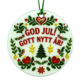 Round Scandinavian ceramic ornament featuring GOD JUL! GOTT NYTT ÅR! text surrounded by traditional floral, heart, and evergreen tree illustrations.