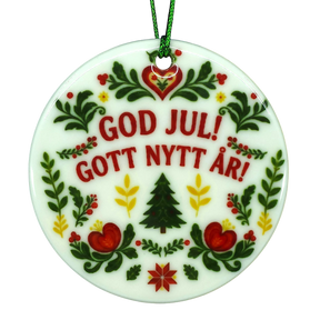 Round Scandinavian ceramic ornament featuring GOD JUL! GOTT NYTT ÅR! text surrounded by traditional floral, heart, and evergreen tree illustrations.