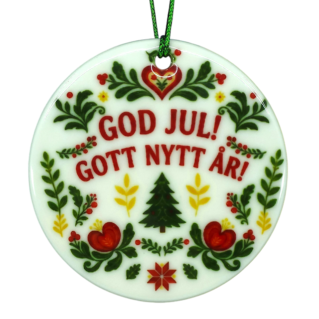 Round Scandinavian ceramic ornament featuring GOD JUL! GOTT NYTT ÅR! text surrounded by traditional floral, heart, and evergreen tree illustrations.