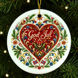 Nordic Christmas ornament featuring a red heart, floral patterns, and “God Jul” text. Two small Norwegian flags are positioned at the bottom. Ornament hangs on a tree.