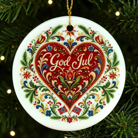 Nordic Christmas ornament featuring a red heart, floral patterns, and “God Jul” text. Two small Norwegian flags are positioned at the bottom. Ornament hangs on a tree.