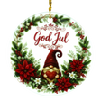 Round ornament with “God Jul,” showing a gnome holding a heart inside a wreath of poinsettias, pine, berries, and white flowers in a Nordic holiday style.