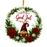 Round ornament with “God Jul,” showing a gnome holding a heart inside a wreath of poinsettias, pine, berries, and white flowers in a Nordic holiday style.