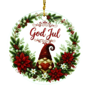 Round ornament with “God Jul,” showing a gnome holding a heart inside a wreath of poinsettias, pine, berries, and white flowers in a Nordic holiday style.
