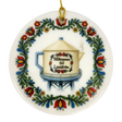 The Nordic Wholesale Ornament: Lindstrom Water Tower Floral Ceramic Ornament (2.875" Diameter) is a round Swedish ceramic ornament featuring a kurbits folk art floral border and the iconic Lindström water tower in the shape of a teapot, accented with the Swedish text “Välkommen till Lindström.” A gold string is attached at the top for hanging.