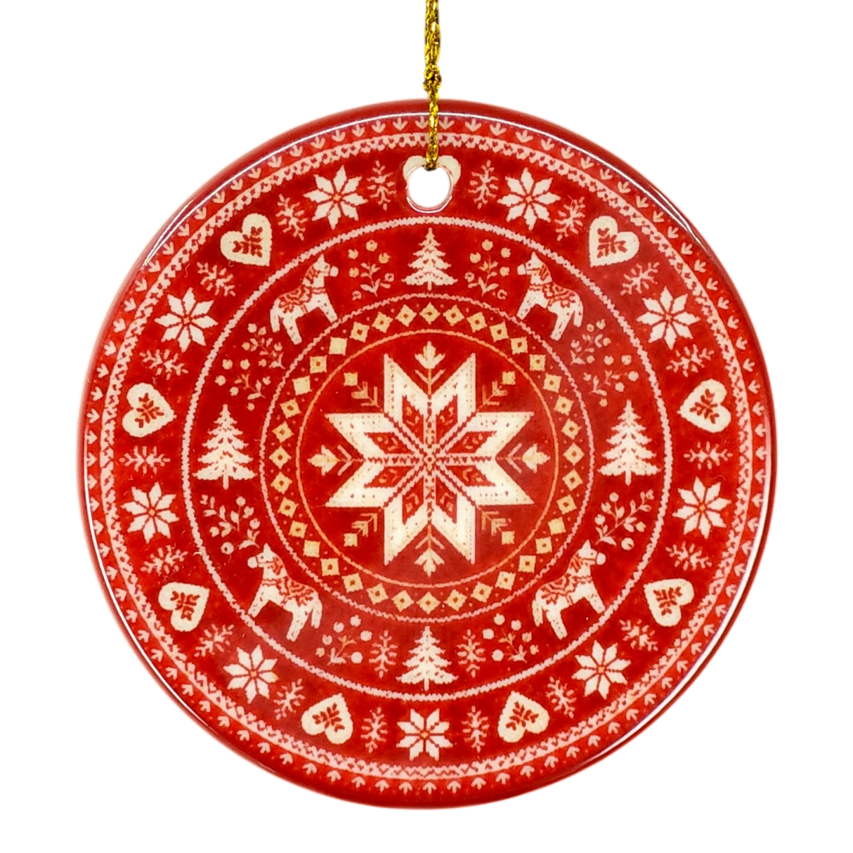 Round red Nordic ornament featuring white snowflake, reindeer, and tree patterns, hanging from a gold string.