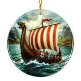 Round ceramic ornament with a Viking longship, red-and-white striped sail, ocean waves, distant mountains, and cloudy sky; hangs from a gold string.