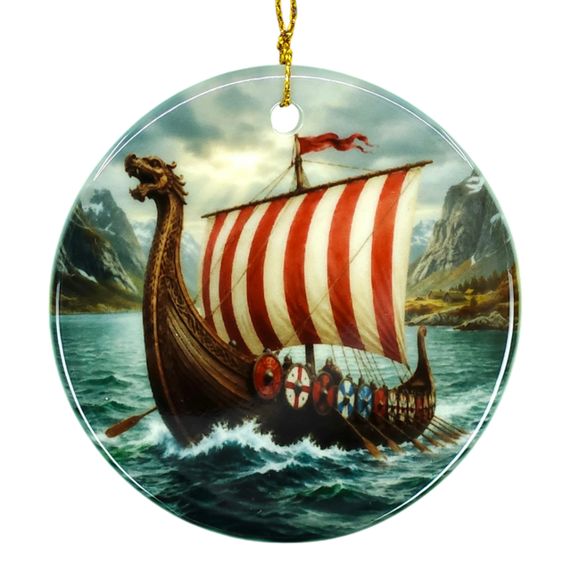 Round ceramic ornament with a Viking longship, red-and-white striped sail, ocean waves, distant mountains, and cloudy sky; hangs from a gold string.