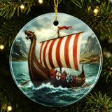 Ceramic Viking ship ornament with a red and white sail, water below, and mountains behind, hanging on a lit Christmas tree.