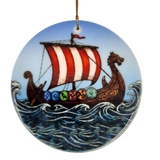 The Ornament: Viking Ship Ceramic Ornament (2.875" Diameter) by Nordic Wholesale features a round design depicting a ceramic longship with a red and white sail, dragon-shaped prow, and vibrant shields gliding through waves under a blue sky—perfect for creating striking Norse holiday décor. This ornament hangs elegantly by a gold string.