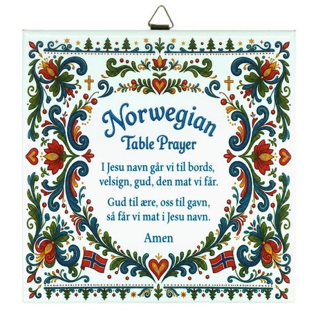 Ceramic wall tile featuring floral rosemaling patterns, Norwegian flags, and a Norwegian Table Prayer in blue text on a white background.