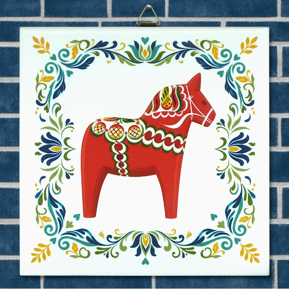Ceramic tile featuring a red Swedish Dala horse with decorative patterns, centered within a blue brick border and surrounded by colorful floral motifs.