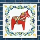 Ceramic tile featuring a red Swedish Dala horse with decorative patterns, centered within a blue brick border and surrounded by colorful floral motifs.