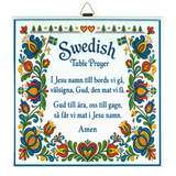 Kurbits trivet featuring floral patterns, Swedish flags, and the Swedish Table Prayer printed in both Swedish and English, ending with the word “Amen.”.