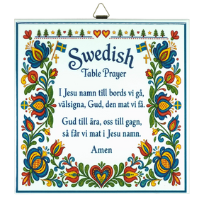Kurbits trivet featuring floral patterns, Swedish flags, and the Swedish Table Prayer printed in both Swedish and English, ending with the word “Amen.”.