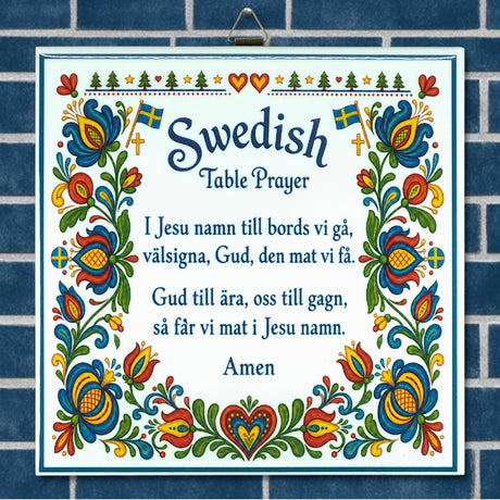 Decorative sign on blue tiles with the Swedish Table Prayer, colorful florals, hearts, flags, and kurbits motifs in a Scandinavian style.