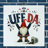 Square Scandinavian wall tile featuring a tomte gnome holding a sign that reads UFF DA, a spilled coffee mug, and floral accents.