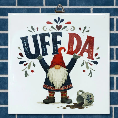 Square Scandinavian wall tile featuring a tomte gnome holding a sign that reads UFF DA, a spilled coffee mug, and floral accents.