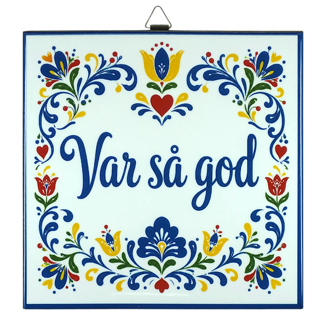 Cork-backed trivet with Norwegian and Swedish folk art patterns in blue, red, and yellow. The words “Var så god” are centered.