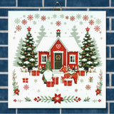 Scandinavian ceramic trivet with red house in snow, gnomes, gifts, trees, and snowflakes, surrounded by holiday greenery on a blue brick-patterned background.