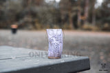 The Horn Mug: Beer Stein Drinking Horn Mug Tree of Life 6-9 oz, featuring a classic design, sits on a rustic outdoor table with trees blurred in the background.