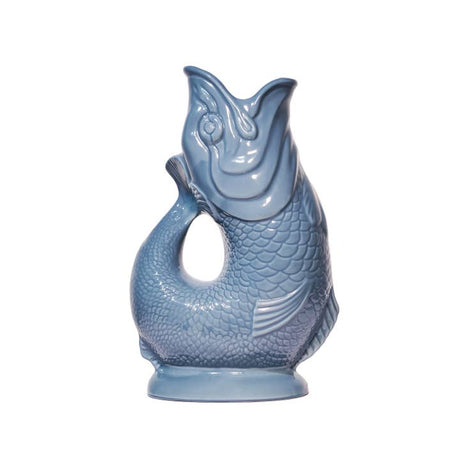 The Gluggle Jug Classic by Faire - The Original Gluggle Jug Factory is a light blue, fish-shaped pitcher with detailed scales, an open mouth, and a curved tail handle, made in Europe and shown on a white background.
