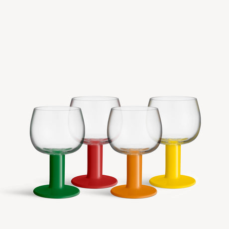 Four mouth-blown glass goblets with solid green, red, orange, and yellow stems and bases.