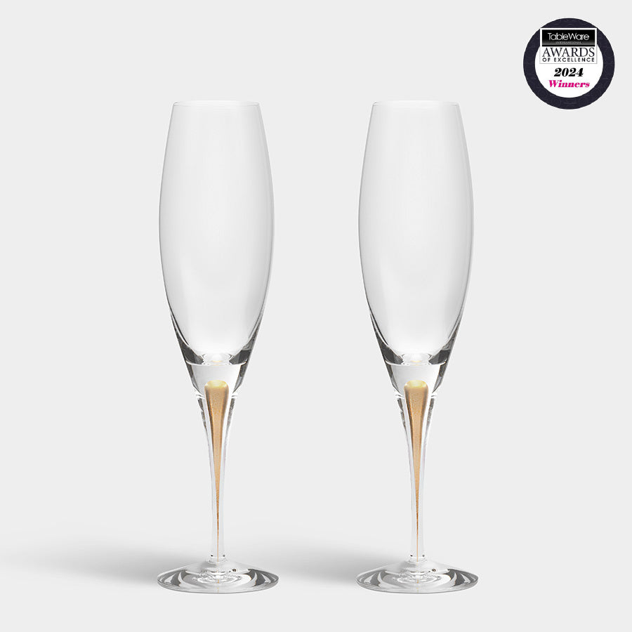 The Orrefors: Intermezzo Gold Champagne Glass (2-Pack) features two elegant flutes with gold accents on a plain white backdrop, displaying a 2024 award winner logo in the top right corner.