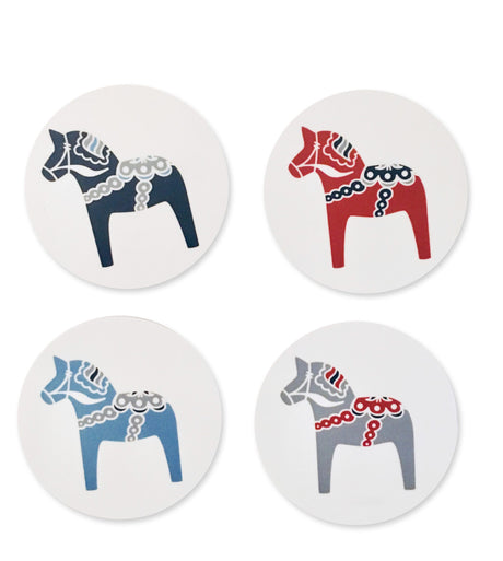 A pack of four coasters, showcasing stylized Dala horse designs in blue, red, and gray on white backgrounds, crafted in Sweden.