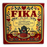 Metal sign with “FIKA” and Swedish coffee break definition, featuring hearts, flowers, coffee cups, teapot, and pastry in red, yellow, and black Scandinavian-style design.