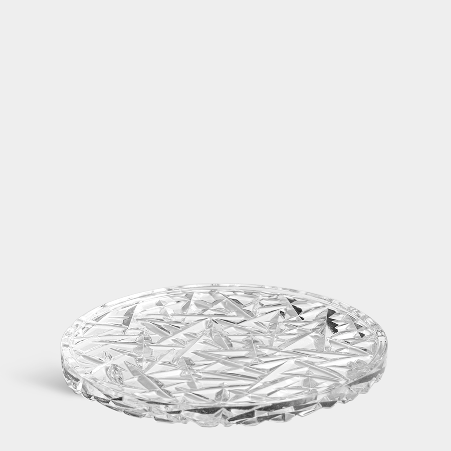 The Orrefors: Carat Coaster Large is made of crystal glass, showcasing a textured geometric pattern elegantly set against a light gray background.