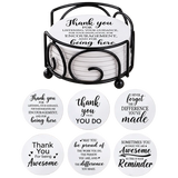 Six round drink coasters each featuring a different gratitude quote in black script, stacked in a black metal holder with a swirl pattern.