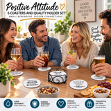 Four people sitting around a table with drinks placed on coasters featuring inspirational words; a decorative box holds additional coasters.