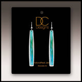 A pair of aqua abstract icicle multilayer handmade earrings on a black DC Designs card labeled Handcrafted Jewelry and Wearable Art.