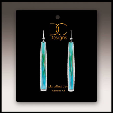 A pair of aqua abstract icicle multilayer handmade earrings on a black DC Designs card labeled Handcrafted Jewelry and Wearable Art.