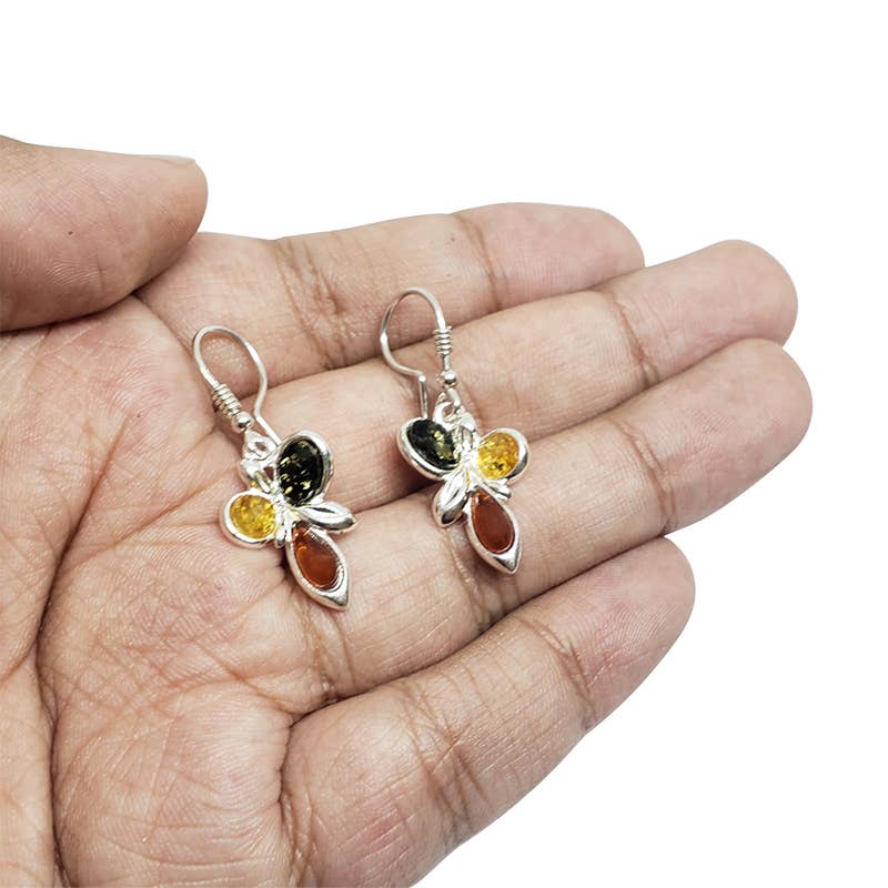 Hand holding sterling silver earrings with oval, round, and teardrop multi-color amber stones on hooks, showcasing the beauty of Baltic Amber in a delicate butterfly design.