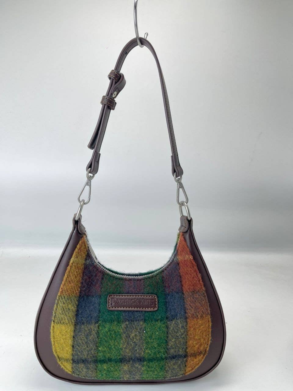 The Bag: Tartan Merino Wool Bag has brown leather trim, a vibrant Antique Buchanan Tartan front, an adjustable strap, and a branded front patch.