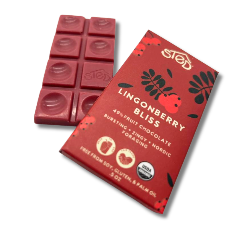 Red chocolate bar with lingonberry pieces next to a wrapper showing Nordic summer berries and icons indicating free from soy, gluten, and palm oil.
