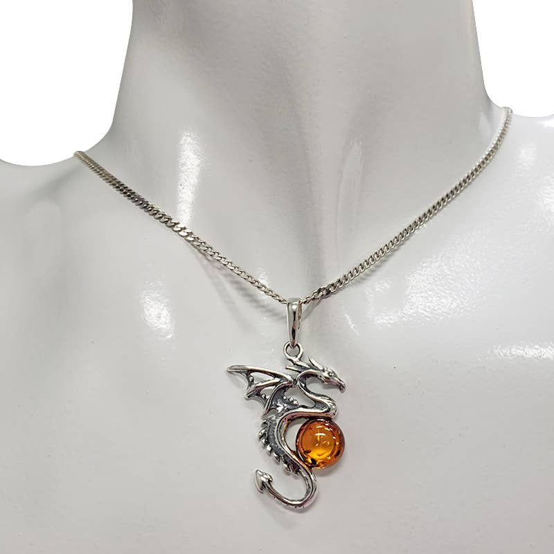 The Pendant: Cognac Amber Silver Dragon Pendant hangs from a silver chain and is elegantly displayed on a white mannequin neck.