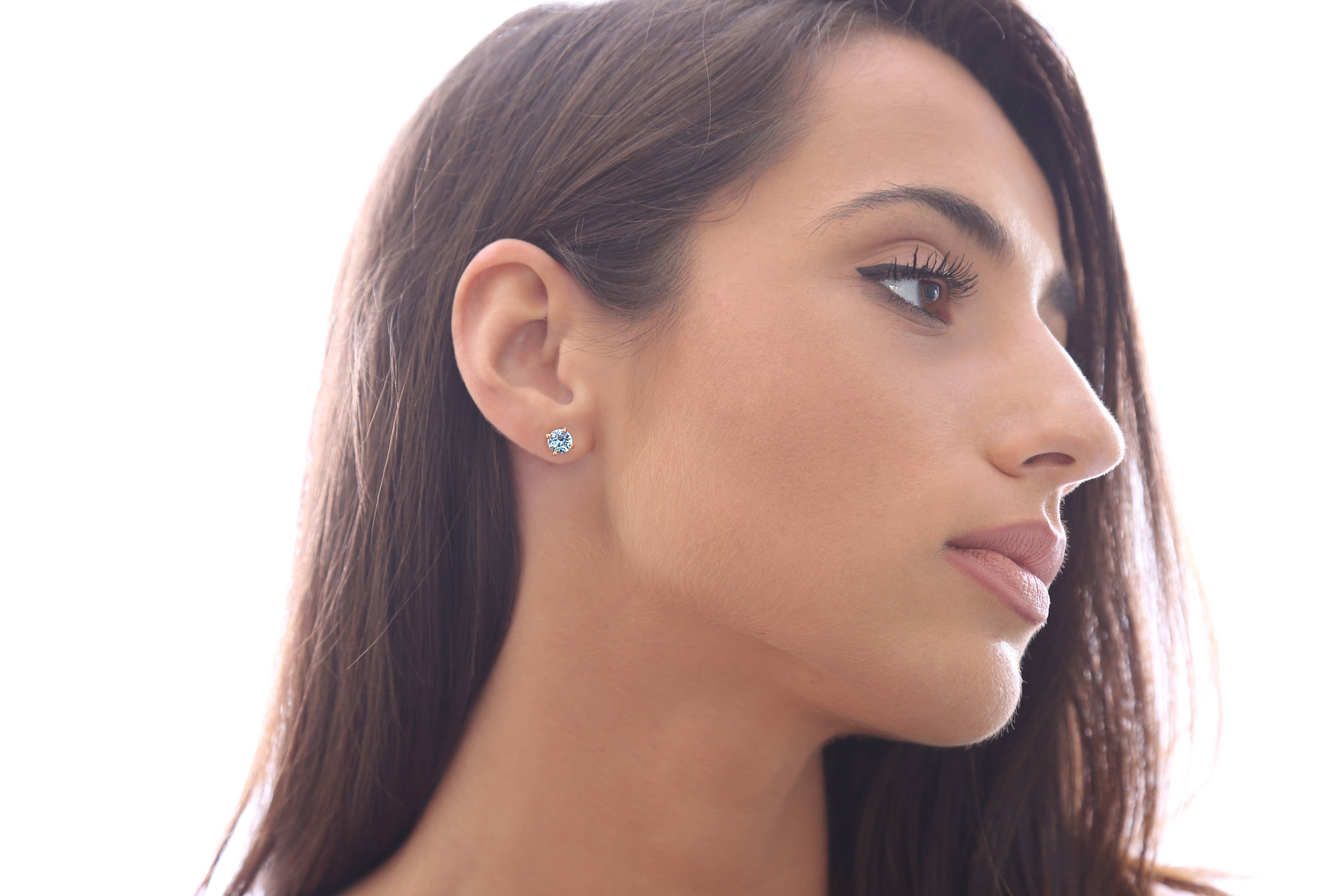 Woman with long brown hair wearing Sapphire Blue Swarovski Crystal Handmade Silver Solitaire Stud earrings, shown in profile against a white background.